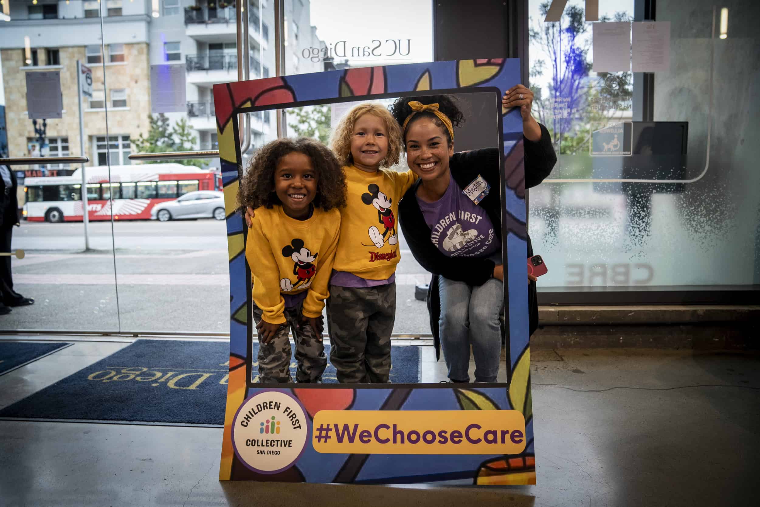 A mother poses with her children with a sign that says We Choose Care